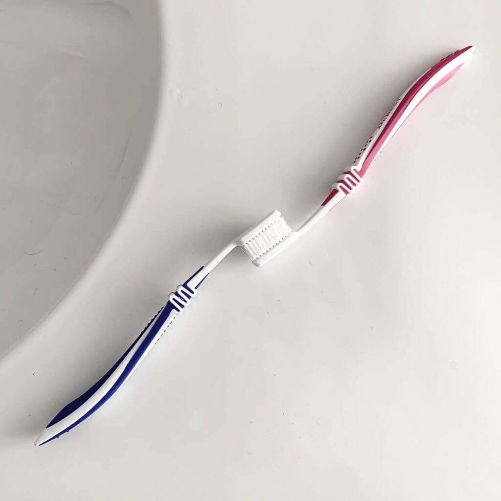 Milen Till hat eine blaue und eine pinkfarbene Zahnbürste an den Borsten miteinander verschränkt. Die Arbeit heißt "L’amour dure 3 minutes".