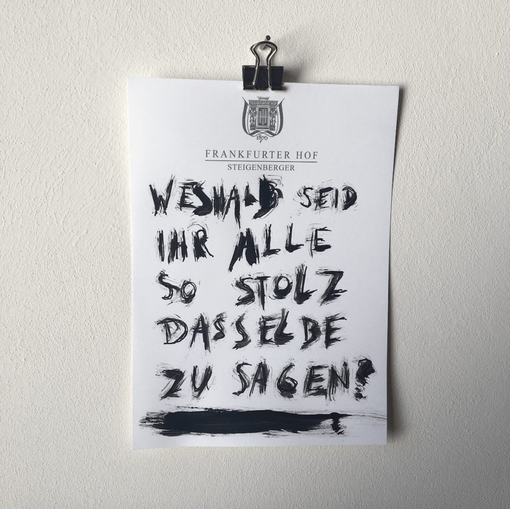 Eine Zeichnung aus der Reihe "Notizen aus der Edelquarantäne" von Künstler Nicholas Warburg. Auf einem Blatt vom Zettelblock des Hotels Frankfurter Hof steht geschrieben: "Weshalb seid ihr alle so stolz dasselbe zu sagen?".