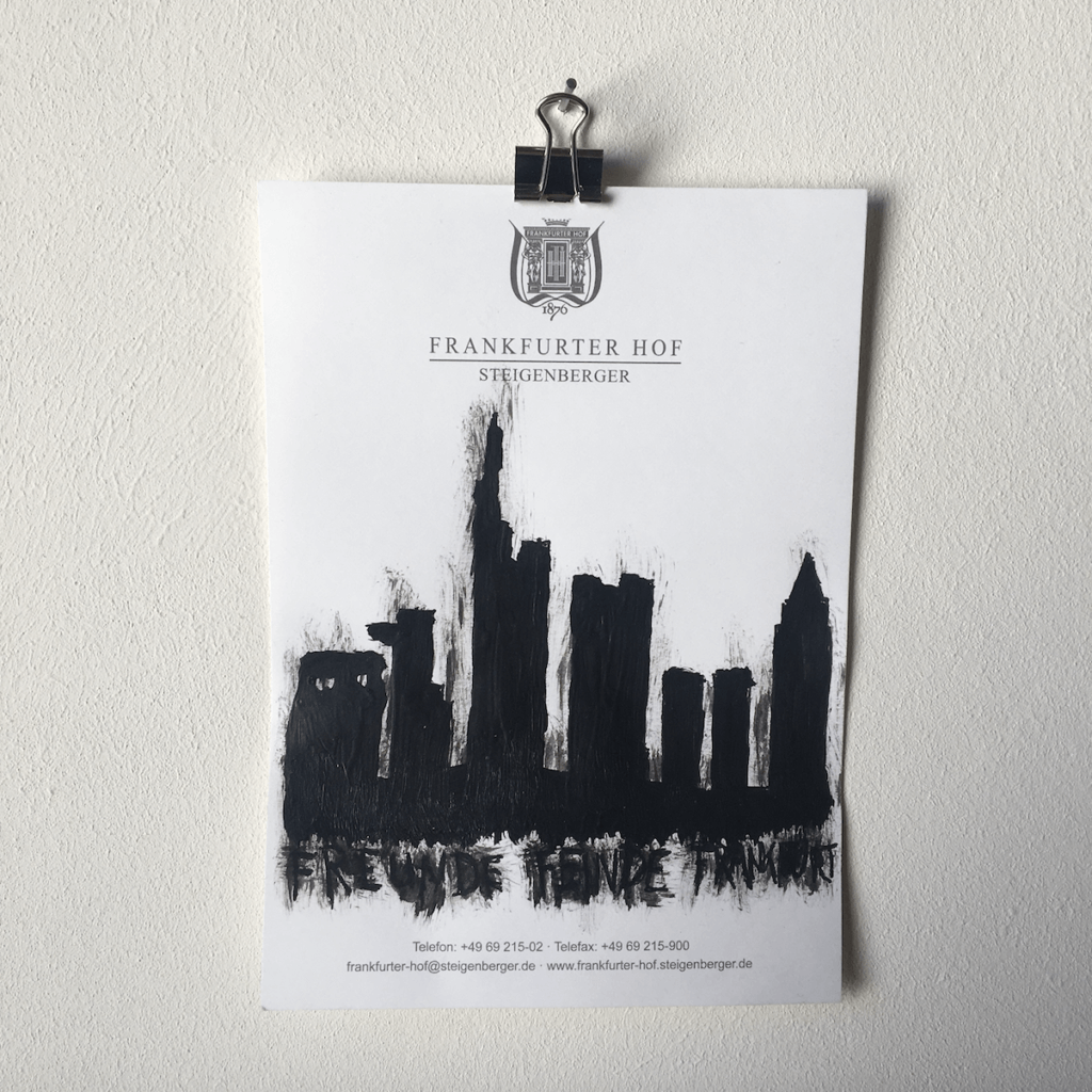 Eine Zeichnung aus der Reihe "Notizen aus der Edelquarantäne" von Künstler Nicholas Warburg. Auf einem Blatt vom Zettelblock des Hotels Frankfurter Hof ist die Skyline von Frankfurt am Main aufgemalt.