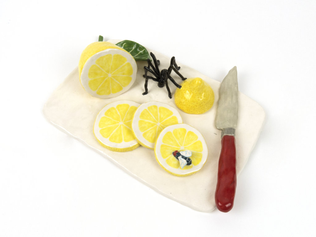 Ein Brett mit Zitronenscheiben sowie einer großen Spinne darauf. Keramik der Künstlerin Katy Stubbs.
