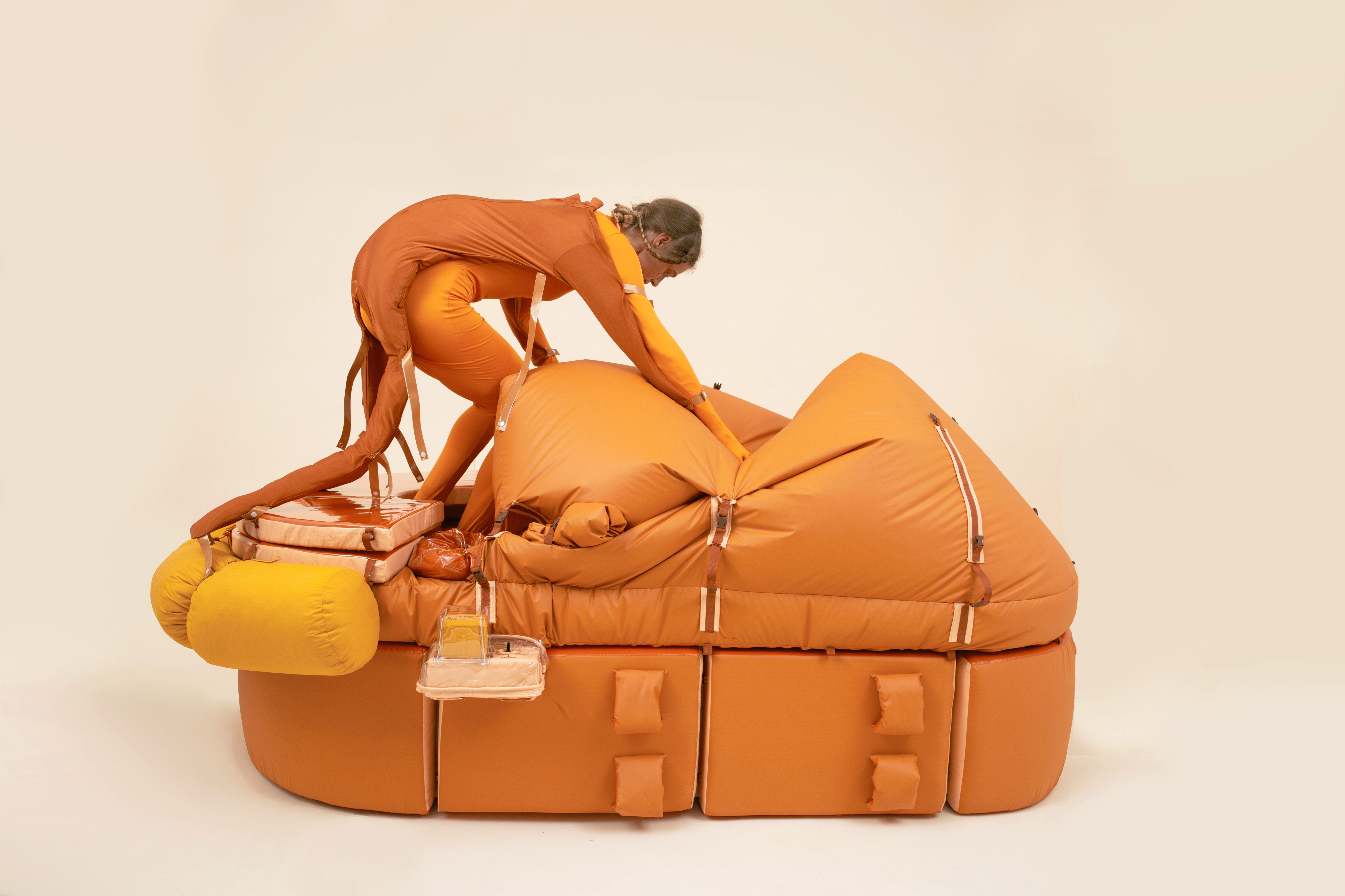 Lucy McRae steigt in ihre Arbeit "Solitary Survival Raft", eine Art orangefarbenes Rettungsboot.