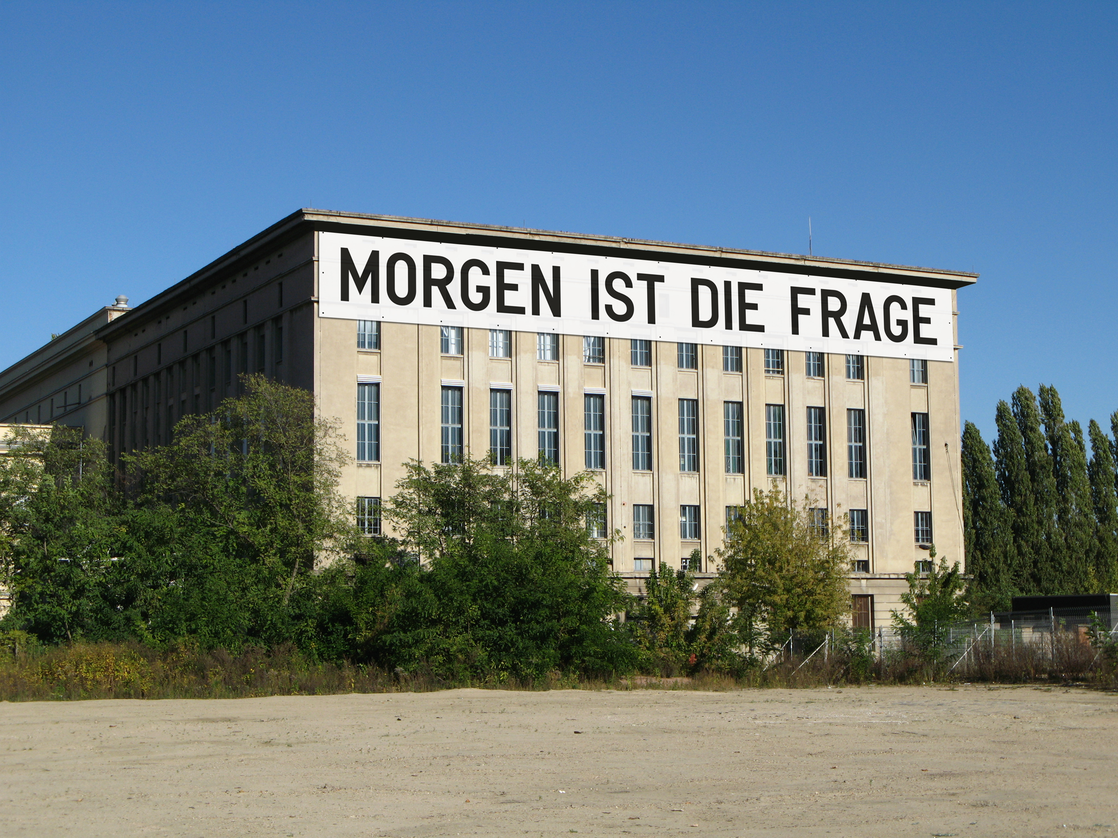 Außenansicht der Berliner Clubs Berghain mit einem Banner von Rirkrit Tiravanija, auf dem steht: MORGEN IST DIE FRAGE.