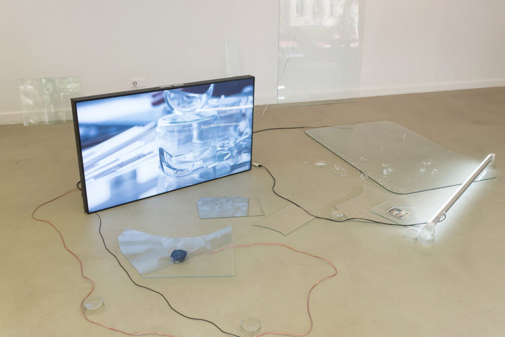 Ein Bildschirm, der auf einem Boden steht, umgeben von Scherben.
