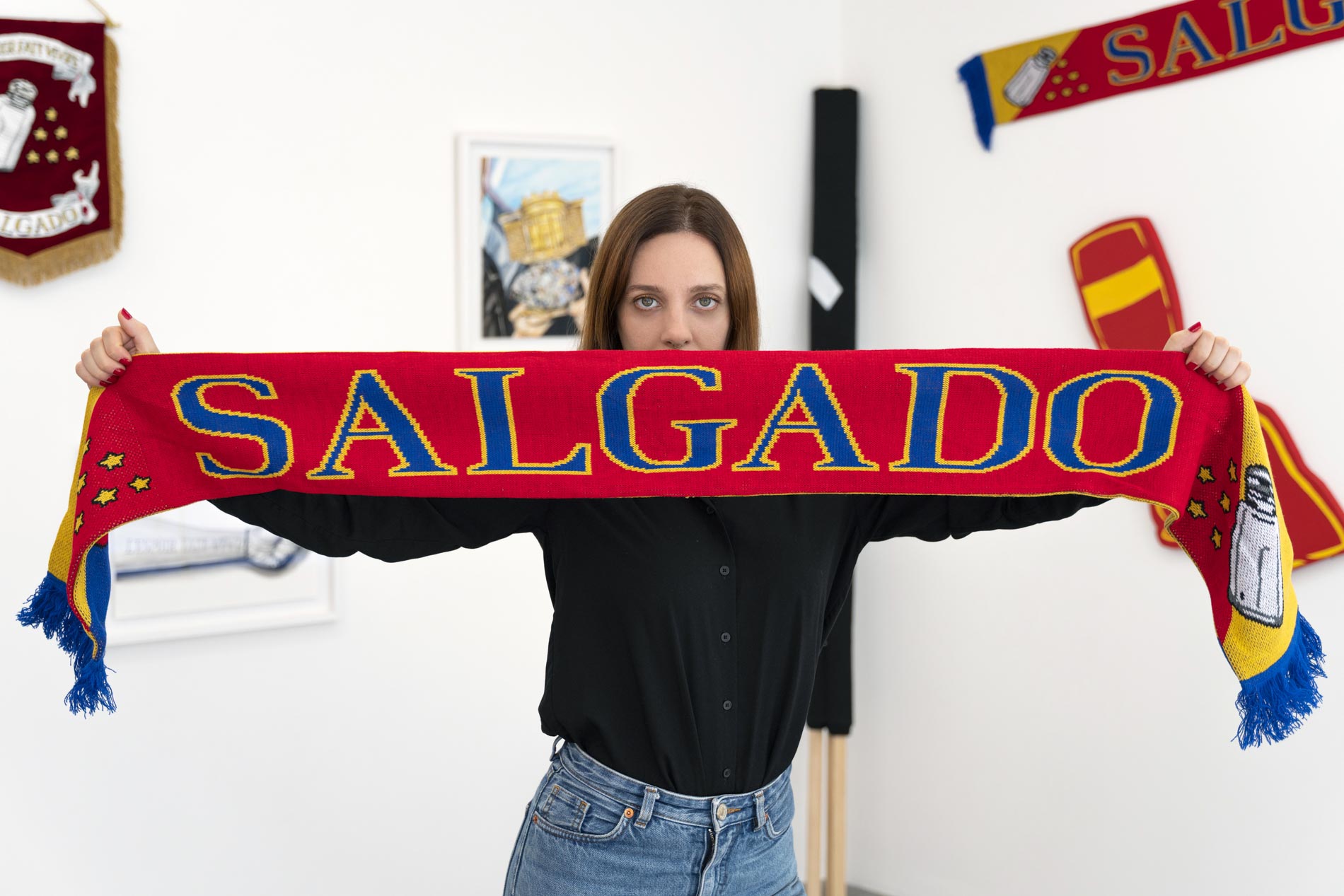 Eine Frau hält einen roten Schal in den Händen, auf dem Salgado steht.
