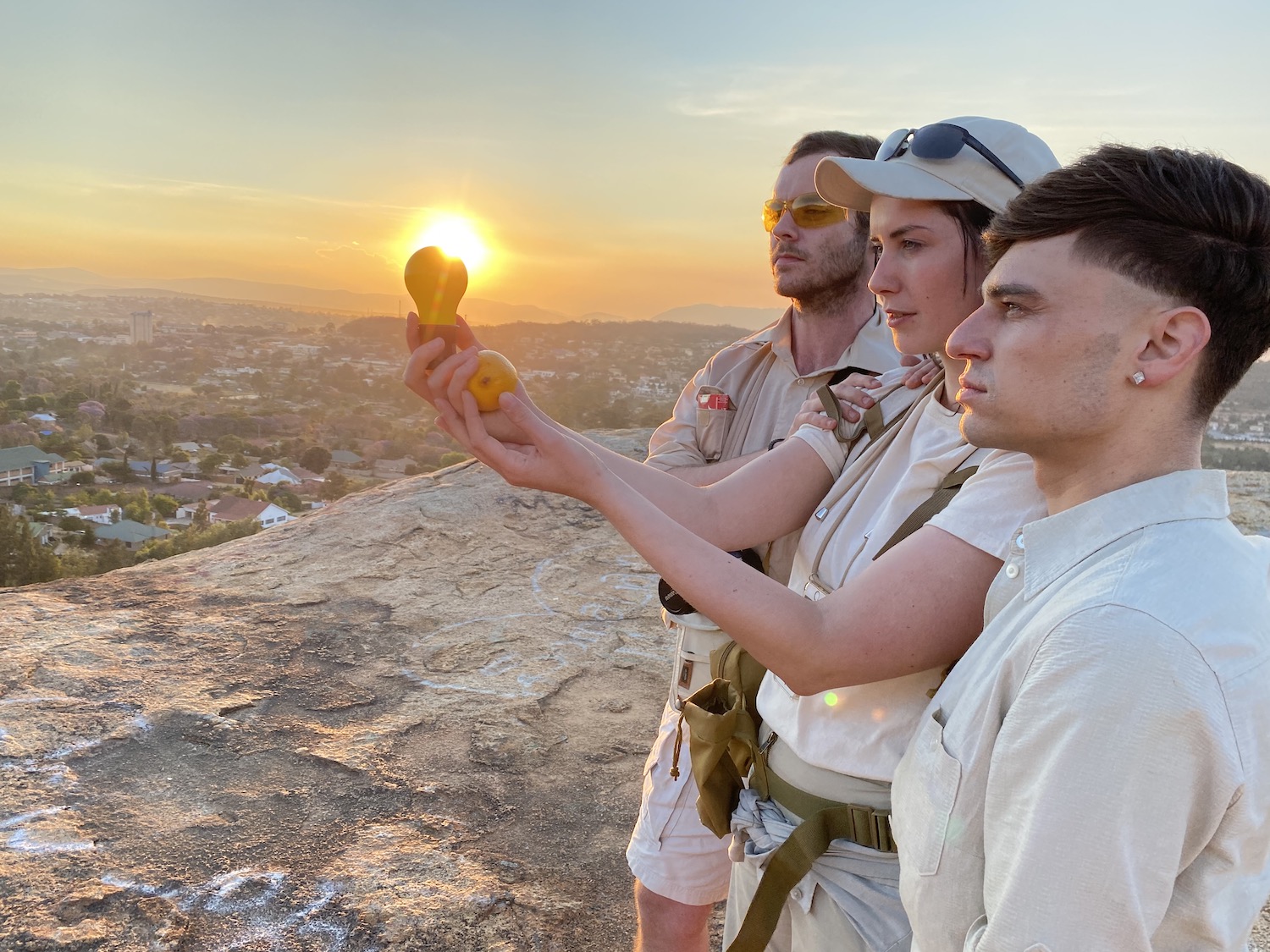 Drei Mitglieder der Frankfurter Hauptschule halten die "Capri Batterie" vor die untergehende Sonne.