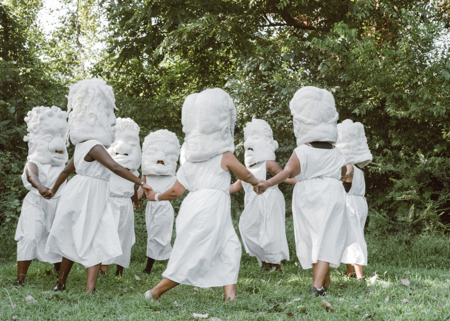 Schwarze Frauen in weißen Kostümen tanzen in der Natur.