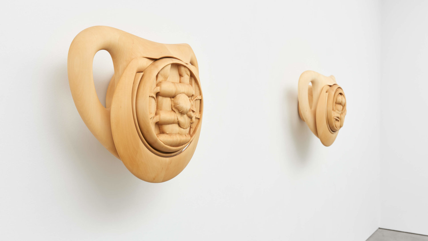 Zwei hölzerne Skulpturen der Künstlerin Anna Uddenberg stellen zwei überdimensionale Schnuller dar, in denen muskulöse Körper in Babykleidung geschnitzt sind.