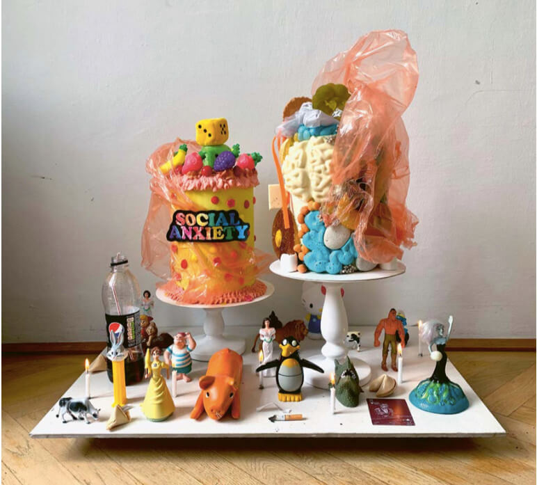 Das Bild zeigt ein Stillleben der Patisserie-Künstlerin Sophia Stoltz, welches zwei Torten und diverse Spielzeug-Figuren in einem gemeinsamen Arrangement zeigt.