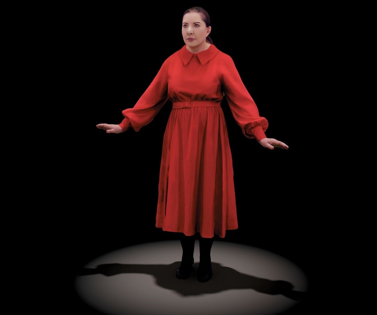Hologramm der Performance-Künstlerin Marina Abramović, die ein rotes Kleid trägt und ihre Arme von sich streckt. Ihr Blick führt an den Betrachtenden vorbei.