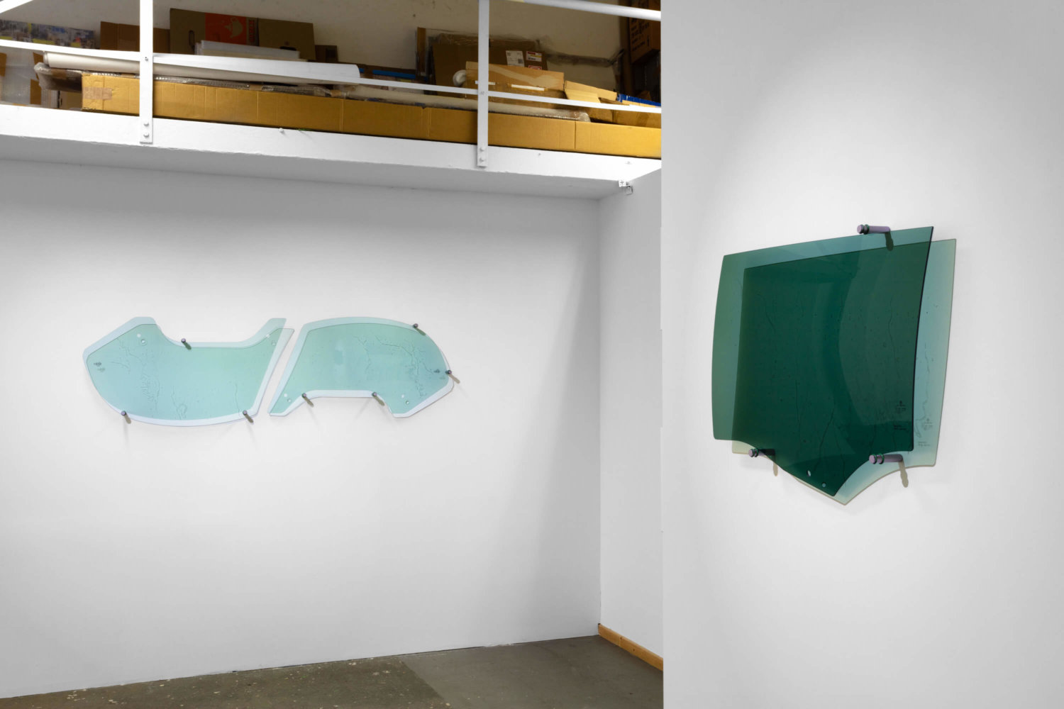 Drei unterschiedlich geformte Autofensterschreiben an weißen Ausstellungswänden