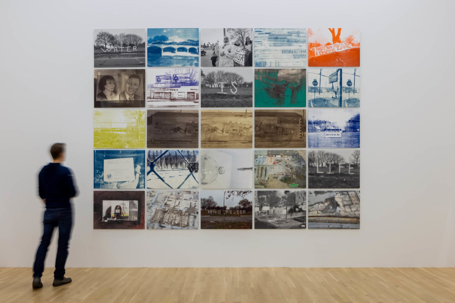 Ausstellungsansicht im Kunstmuseum Wolfsburg, ein Besucher steht vor einer weißen Ausstellungswand mit 25 Fotografien zum Thema Wasser