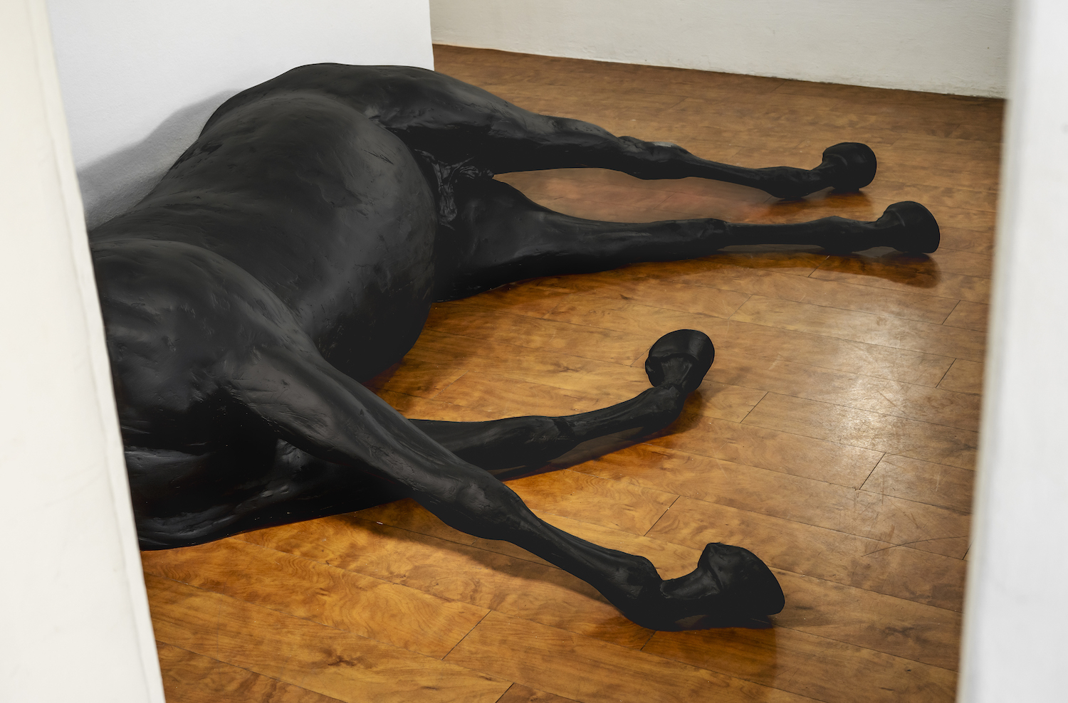 Ein schwarzes Pferd aus Plastik liegt erschöpft am Boden des Neuen Gießener Kunstvereins.