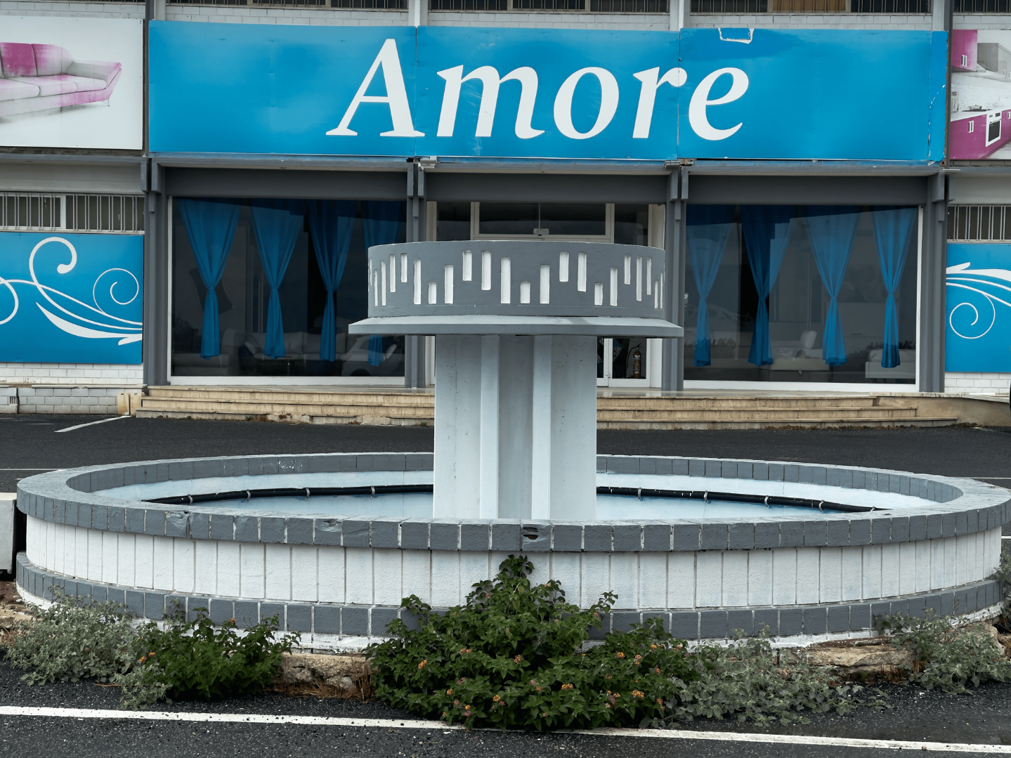 Ein Brunnen, der sich vor einem Laden mit einem großen Schild "Amore" befindet