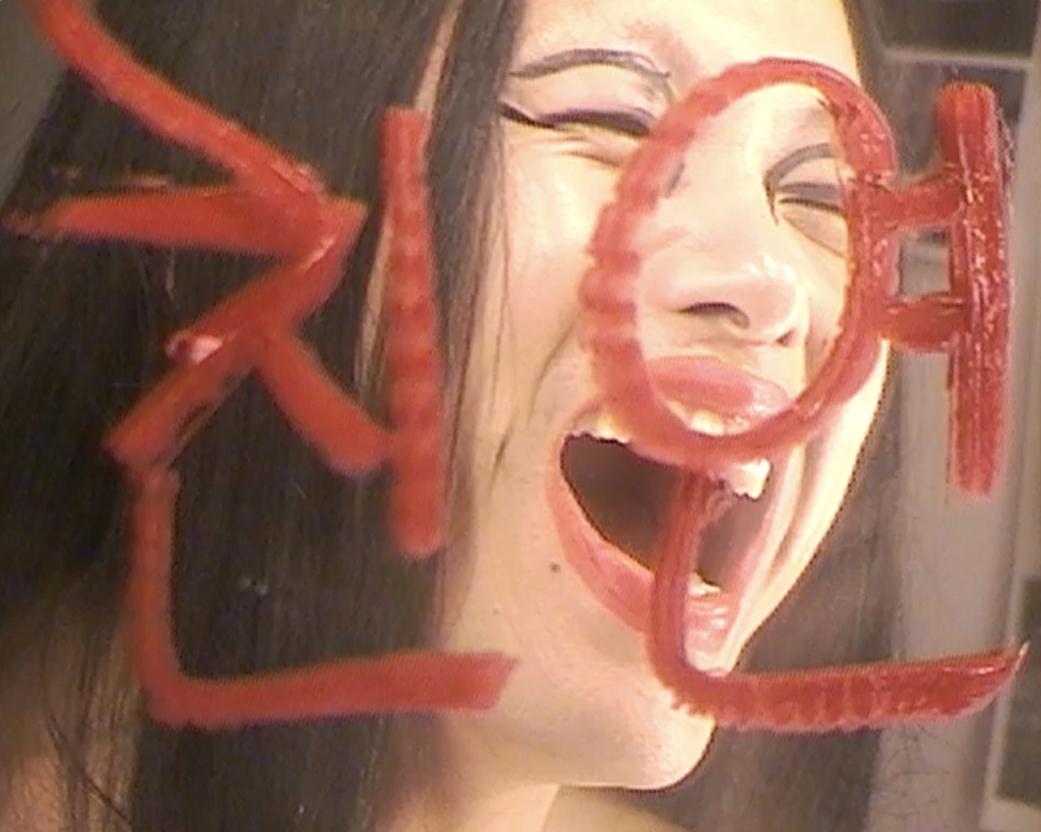 Eine Frau schreit vor einem Spiegel der mit rotem Lippenstift beschrieben ist.
