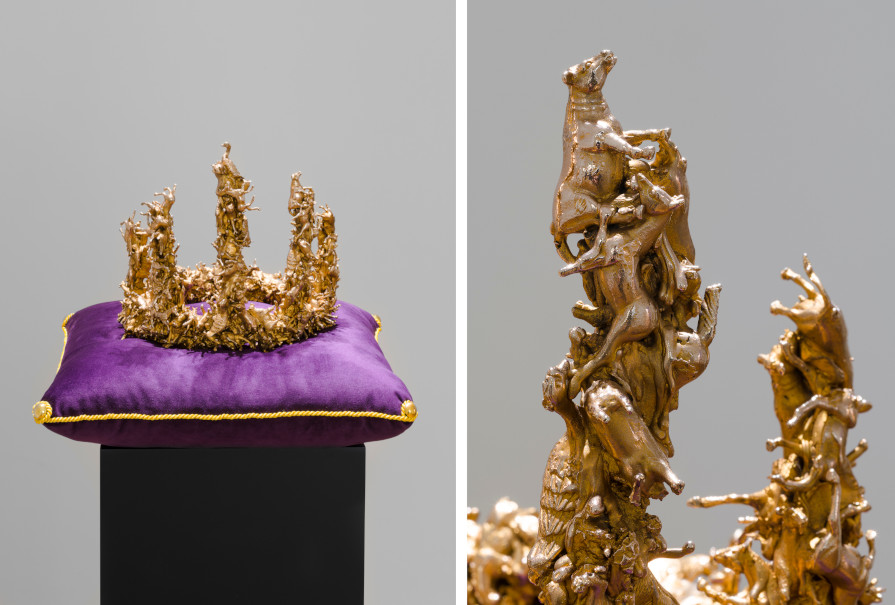 Eine goldene Krone liegt auf einem lila Samtkissen. Sie besteht aus vielen goldenen Spielzeugtieren.