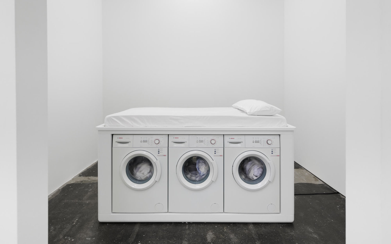 11. BF Galeria Plan B gallerytalkm ein weißes Bett aufgesetzt auf drei laufende Waschmaschinen